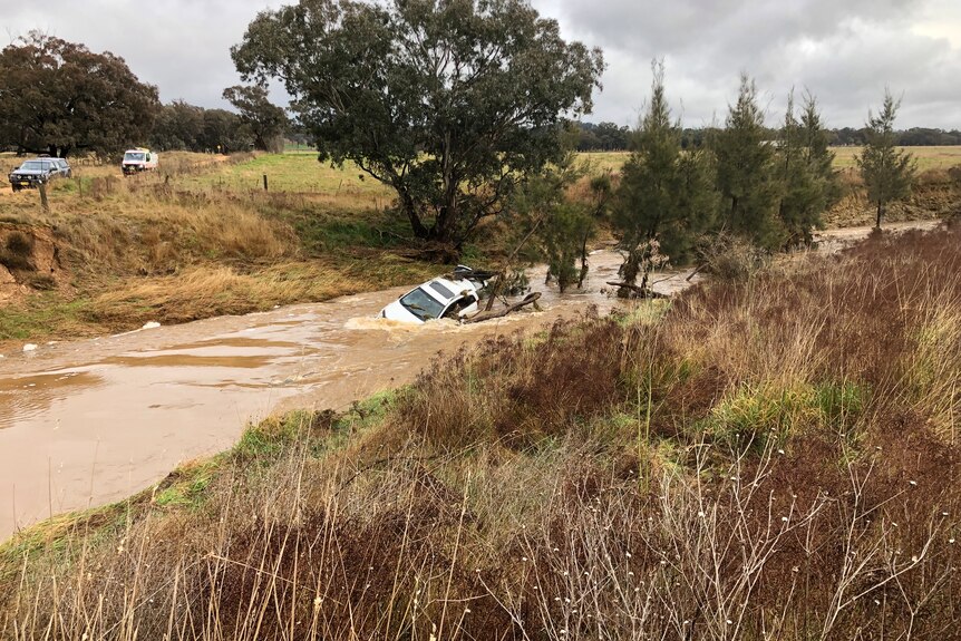 A car submerged in a flooded waterway.