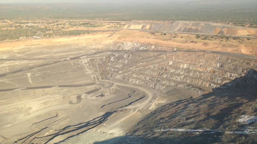 A vast mine quarry made up of grey rock, surrounded by a sparse desert landscape.