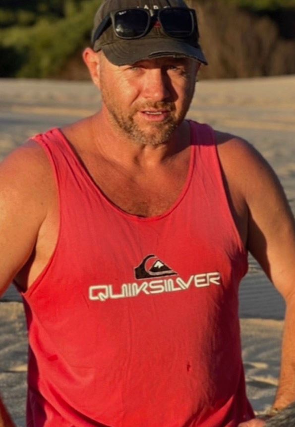 A man wearing a red singlet and dark-coloured cap.
