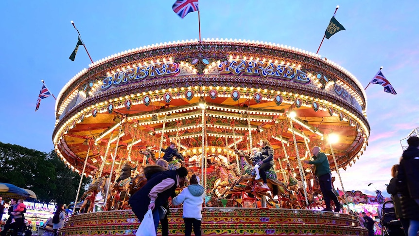 Colourful carousel at night, young family watching on