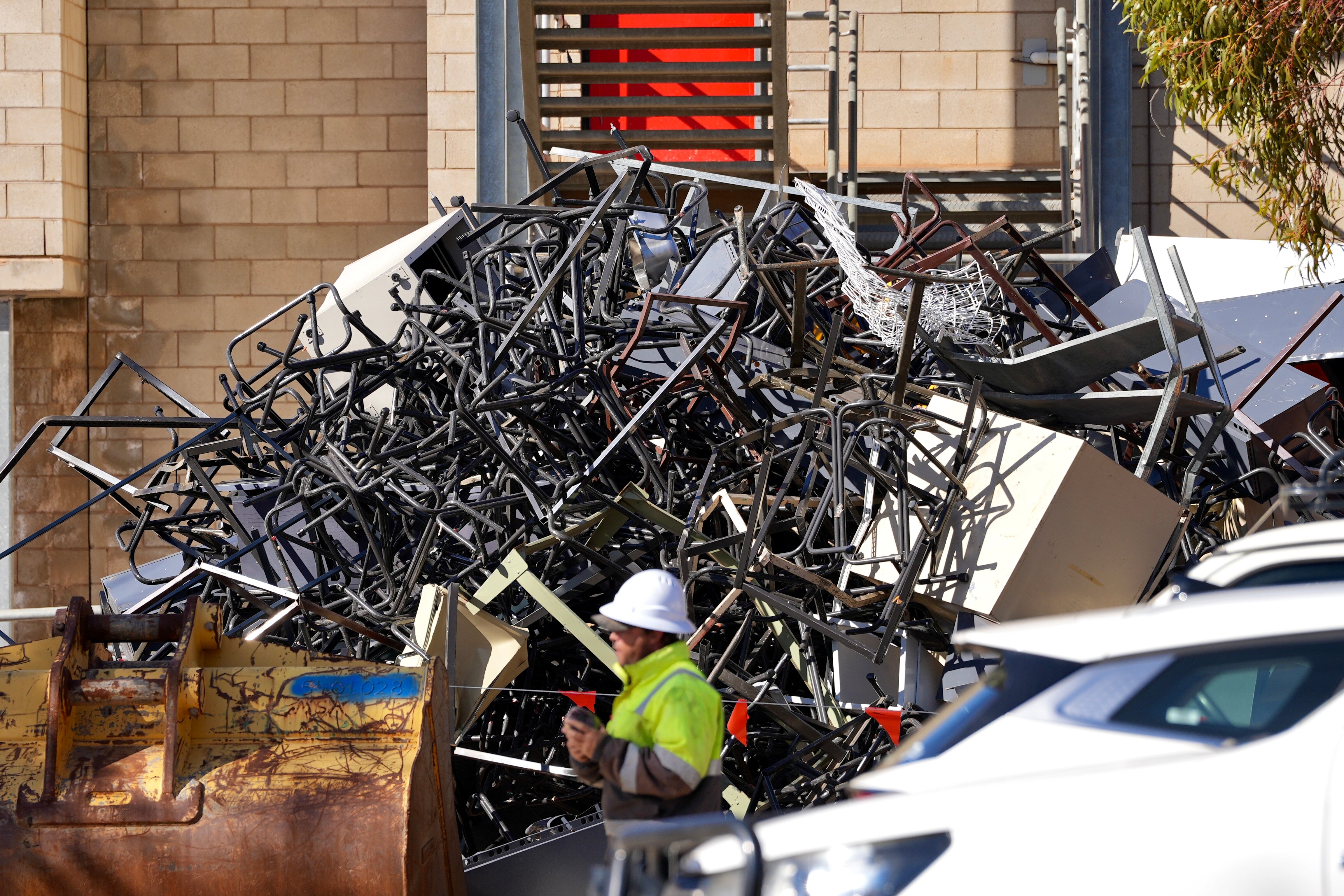 A large pile of metal objects next to construction equipment and a man in a hard hat