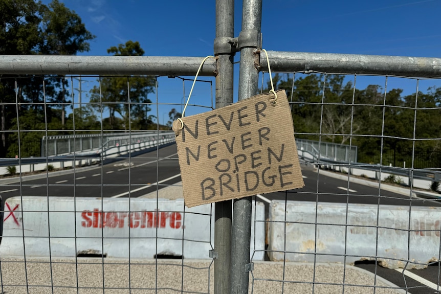 A sign hangs on a bridge that saying "never never open bridge"