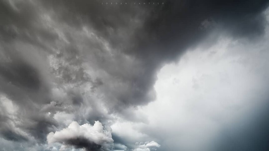 Dark storm clouds form over hills.