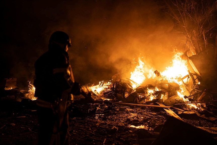 A firefighter works in the night to extinguish a fire in the wreckage of a car hit by a shot down missile. 