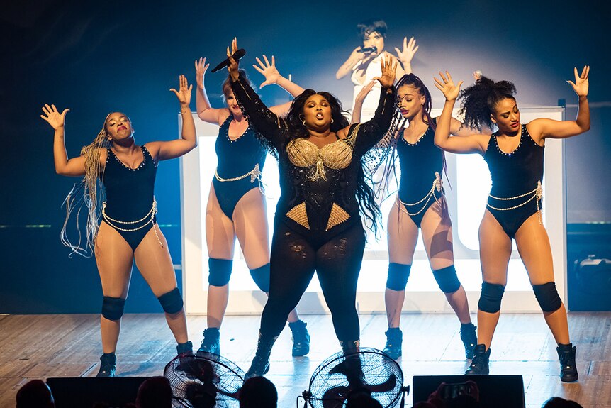 Lizzo and four dancers hold their hands up at the Sydney Opera House