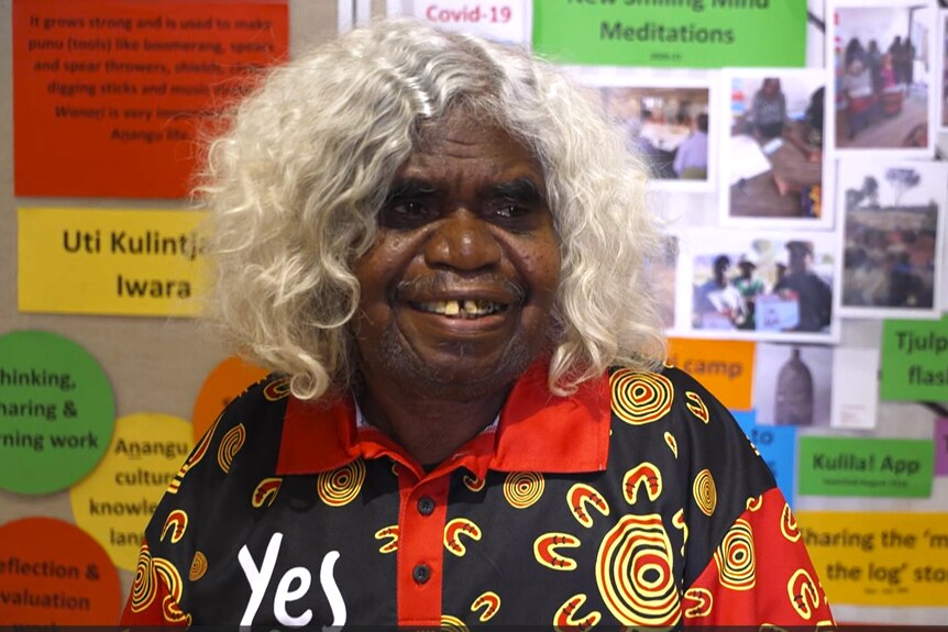 An older Aboriginal woman wearing a shirt that says "Yes" on it. 