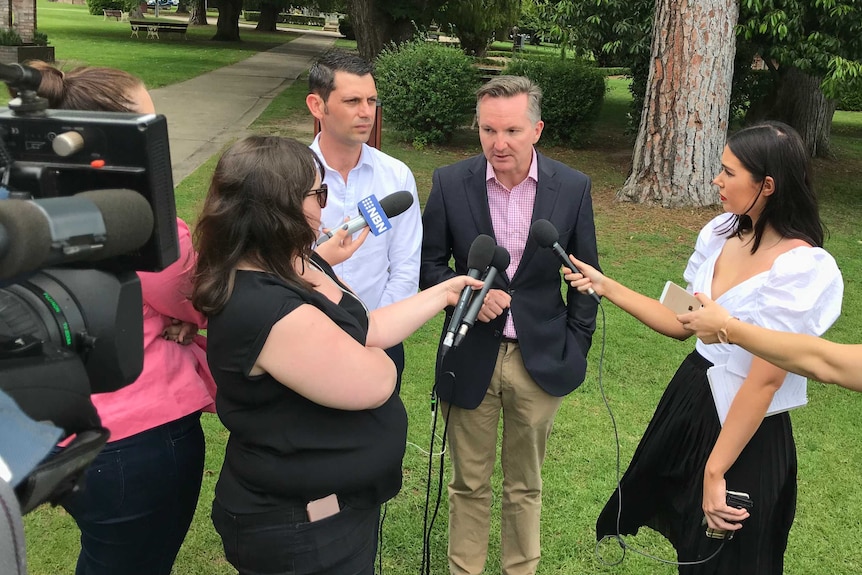 David Ewings and Chris Bowen being interview by journalists in a park.