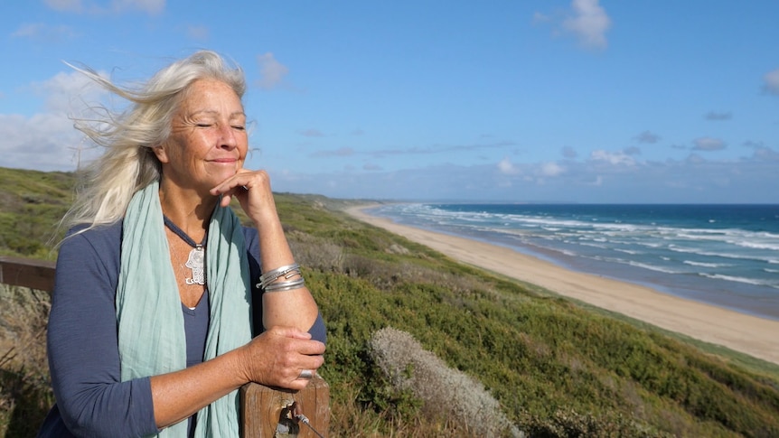 Woman with long grey hair basking in the sun at the beach
