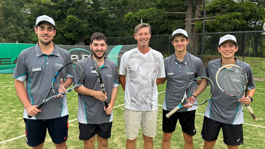 Five men standing on tennis court