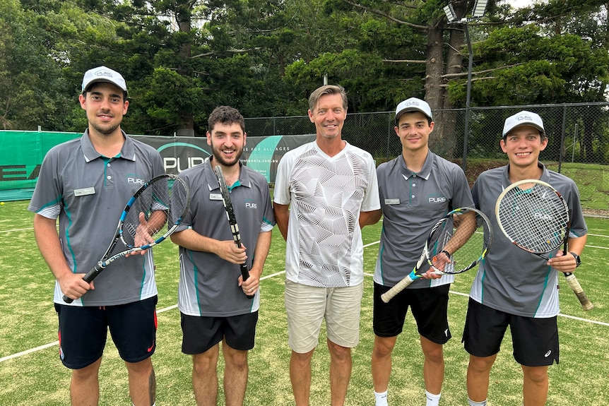 Five men standing on tennis court