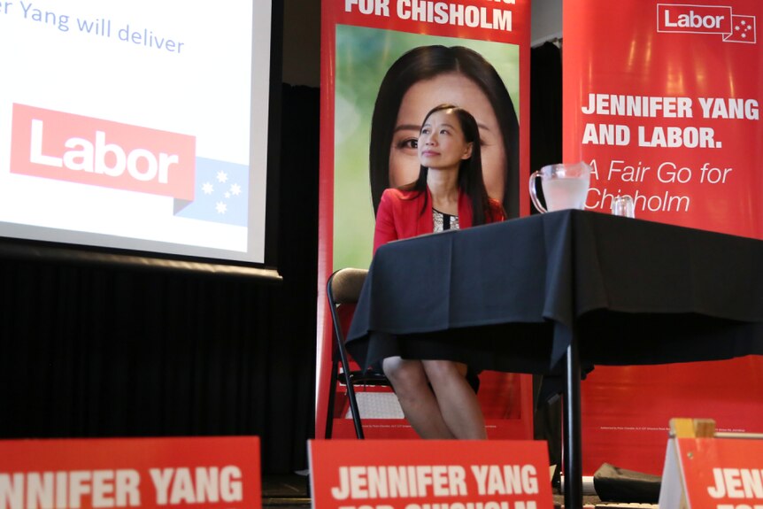 Labor candidate Jennifer Yang sits at a table looking up at a screen at a meet the candidates forum.