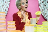 A retro-styled woman poses with Tupperware-style food containers