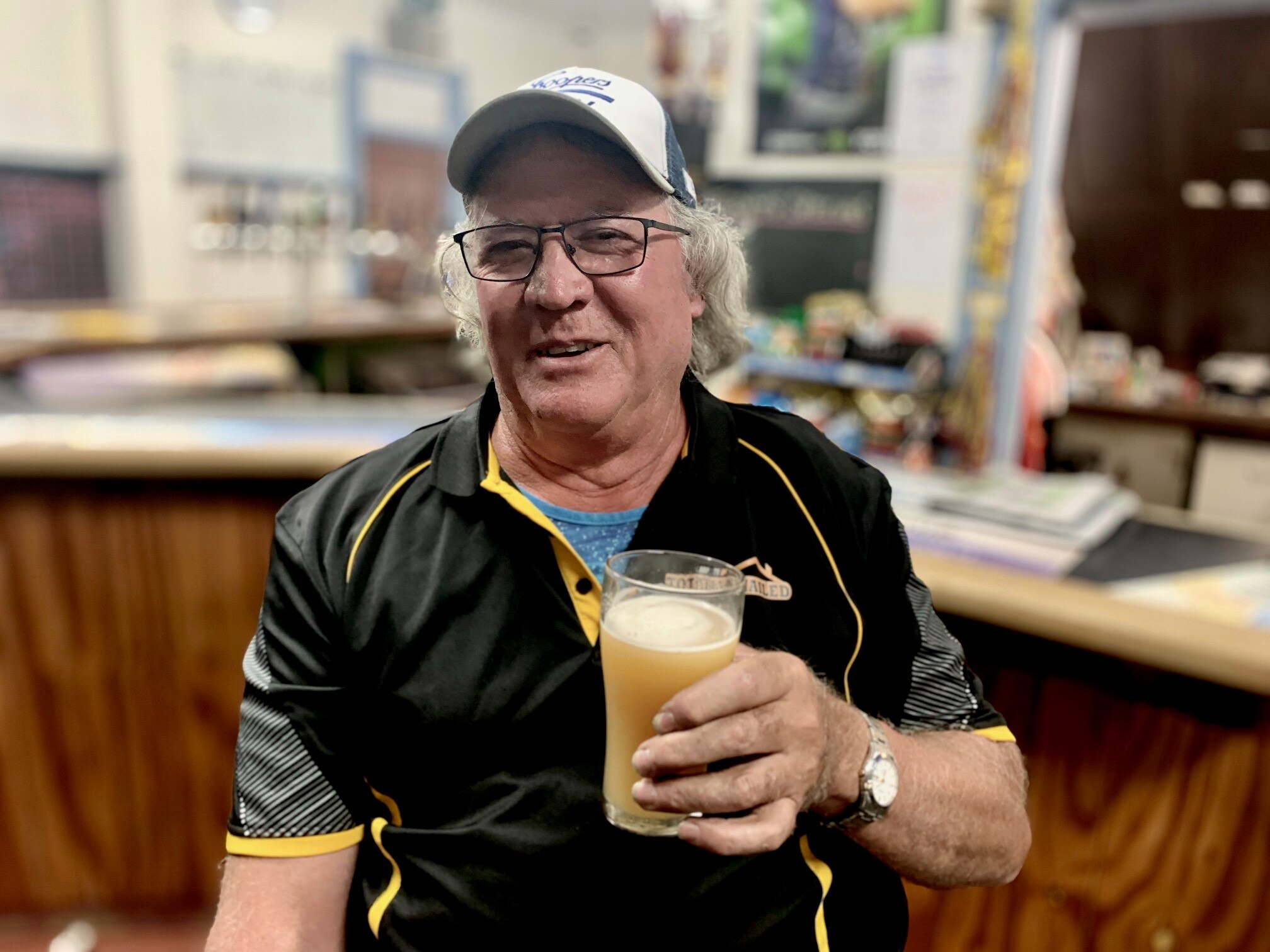 A man wearing a cap holding a beer.