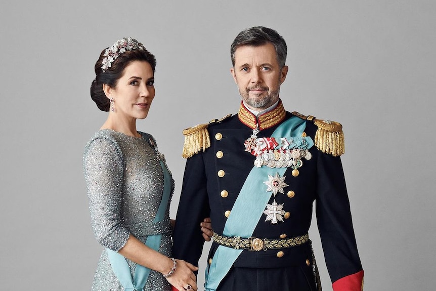 A man in military dress and a woman in an ice blue evening gown and tiara 