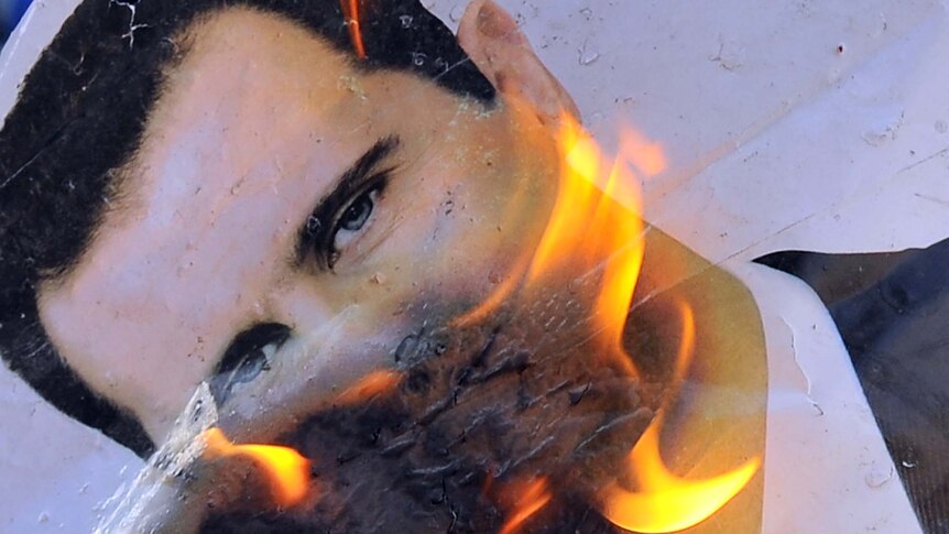A portrait of Syrian President Bashar al-Assad burns