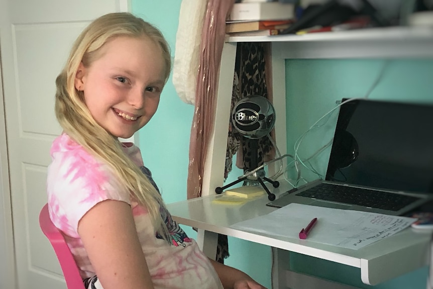 Girl sits at a desk with a computer