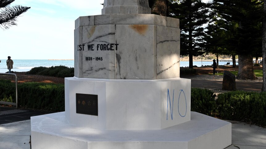 The base of a war memorial has the word no painted on it