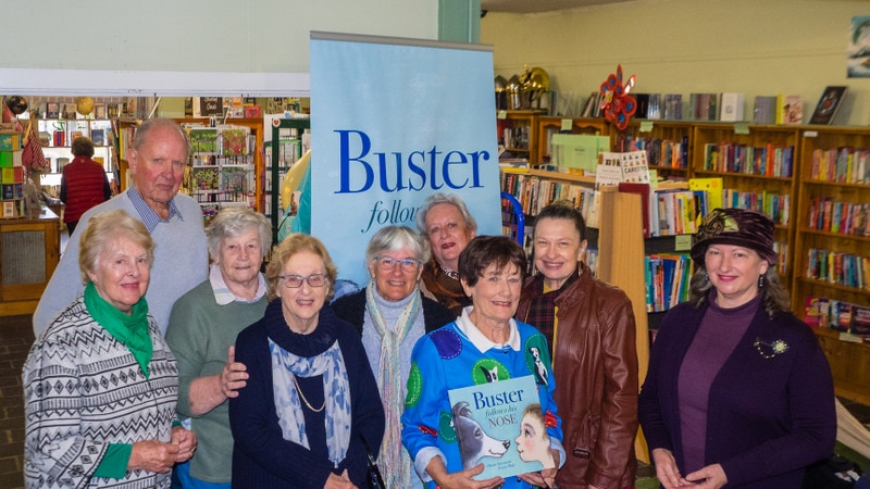 a group of people standing in a book store, author Paula Stevenson holds her new book proudly.