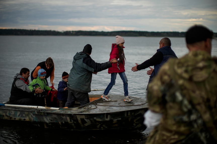 A man helps people to disembark after crossing the Siverskyi-Donets river.