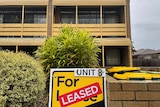 Flor lease sign stamped with giant red Leased sticker in front of block of units. 