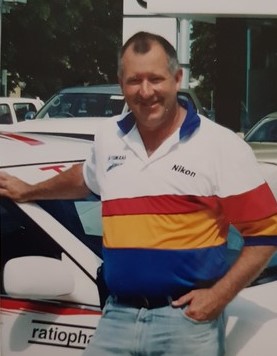 A photo from early 2000s of a older white man in a striped tshirt