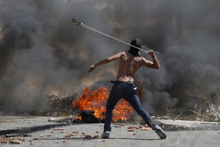 A Palestinian protester uses a sling to hurl stones