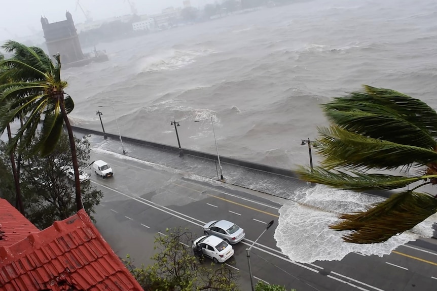 Waves crash onto the road as cars drive past the water as Cyclone Tauktae batters Mumbai, India.