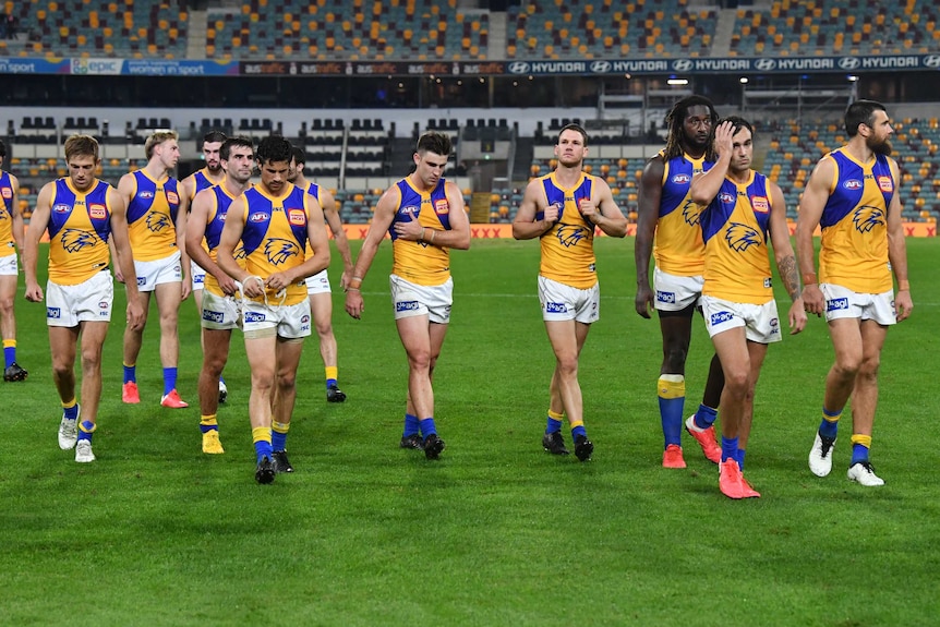 A number of Eagles players look dejected as they walk off the field after losing to Brisbane.