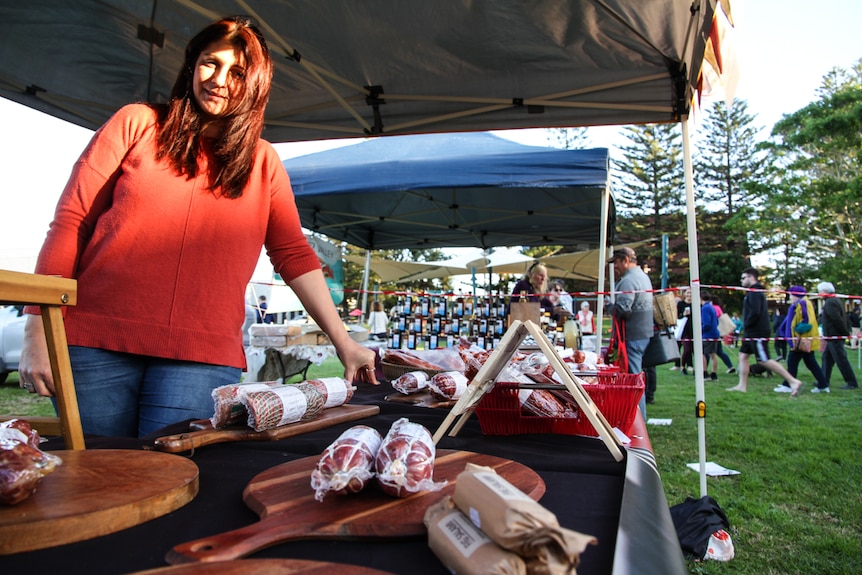 A woman at the market is selling salami