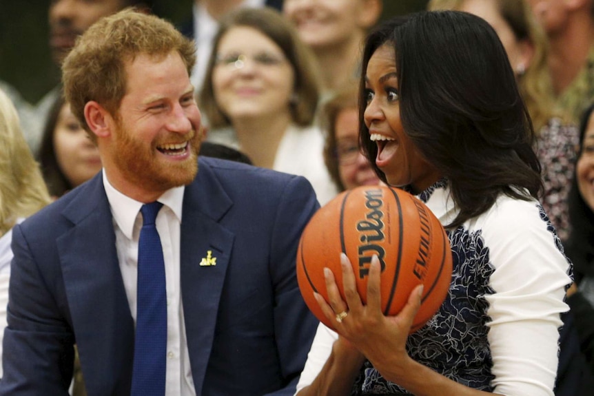 Britain's Prince Harry hands U.S. first lady Michelle Obama the basketball at the end of a game played by wounded warriors at Fort Belvoir