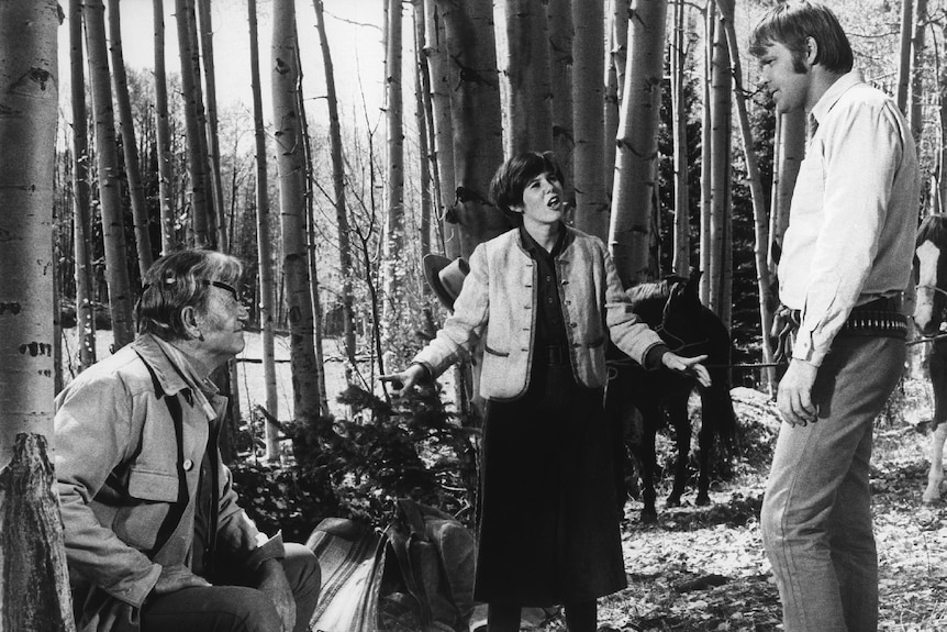 A screenshot of Rooster Cogburn, Mattie Ross and La Boeuf in the woods in the movie True Grit.