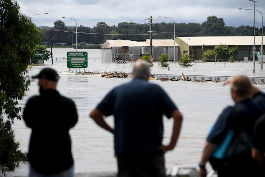 people standing on the banks of a flooded river