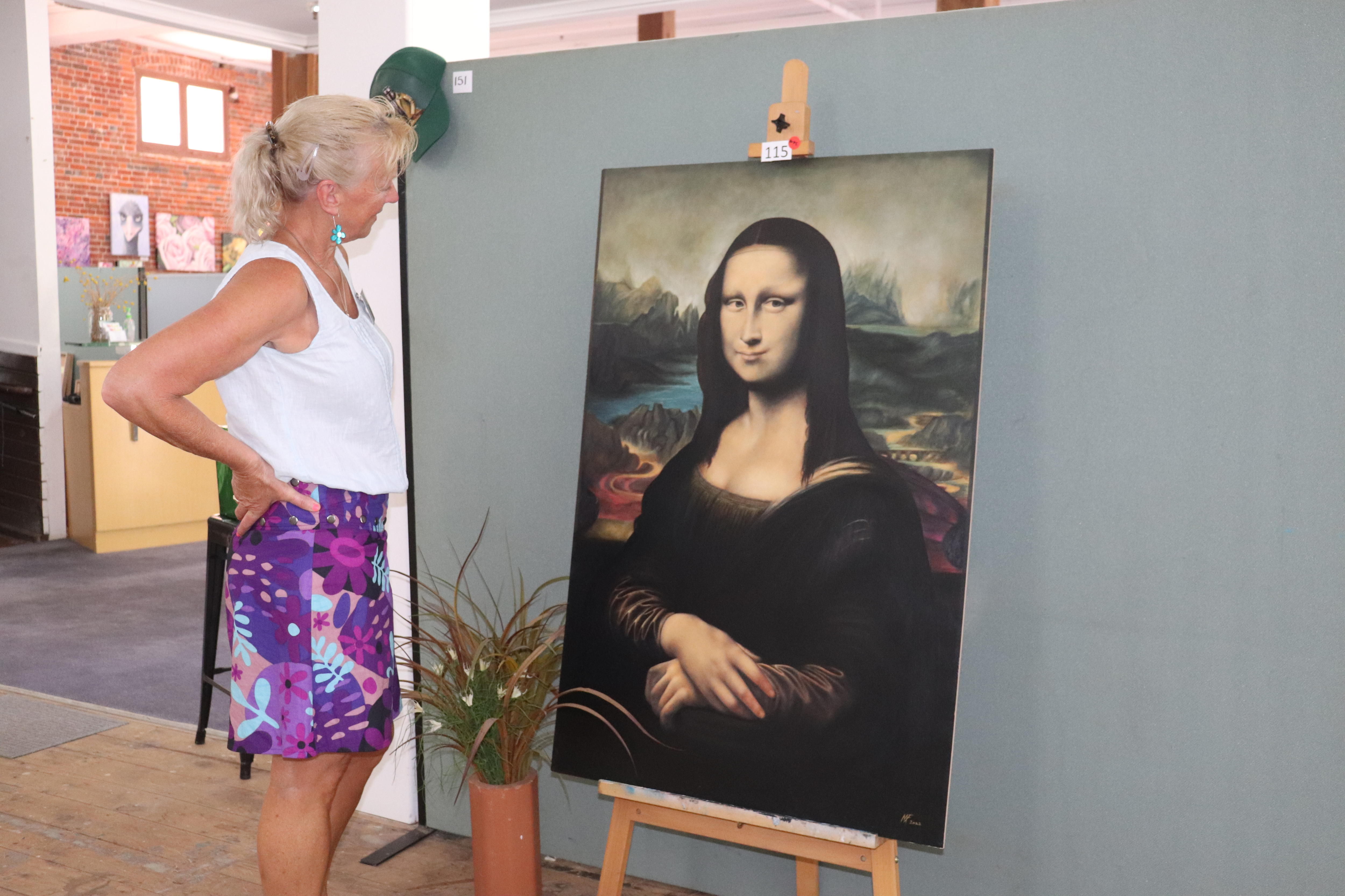 A woman stands looking at a replica of the Mona Lisa painting.