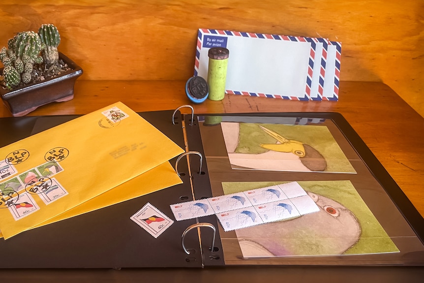 A desk with hand-drawn stamp designs and envelopes.