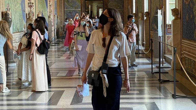 Sybella stands in a church in Rome in a mask surrounded by other tourists. 