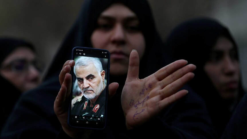 An Iranian woman shows a photo of the late Iranian Major-General Qassem Soleimani, during a protest against his killing.