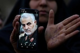 An Iranian woman shows a photo of the late Iranian Major-General Qassem Soleimani, during a protest against his killing.