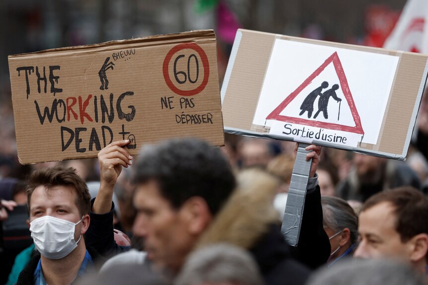 A person holds up a sign that say, 'the working dead'.