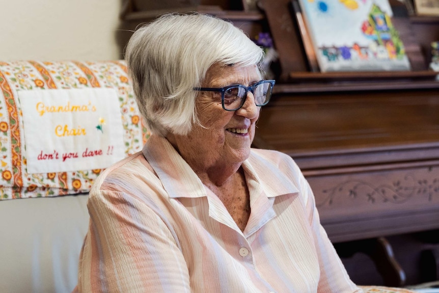 Kay Lockley sits on her chair smiling.