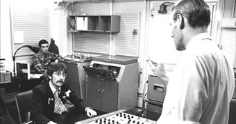 A sound engineer works with John Lennon and George Martin in the Abbey Road studios.