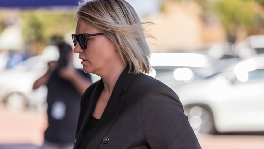 A woman walking into a police station for a court appearance.  