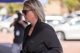 A woman walking into a police station for a court appearance.  