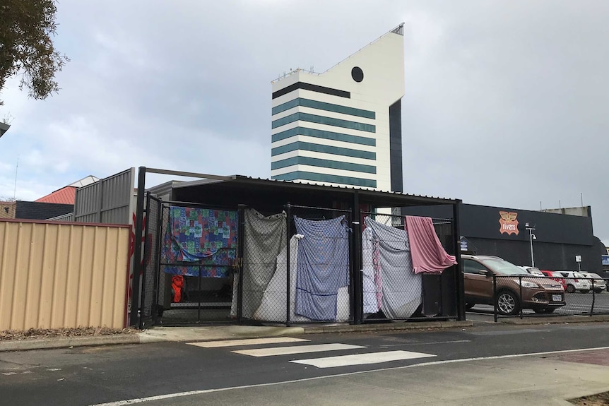 A shelter for Bunbury's homeless community set up in a car park, enclosed with sheets. The Bunbury tower is in the background.