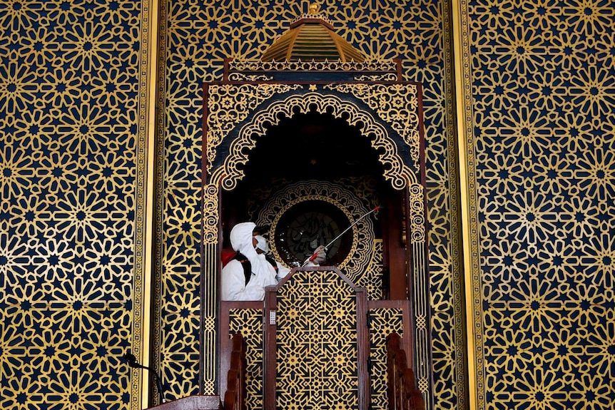 An officer dressed in full body suit sprays a mosque in East Java province.