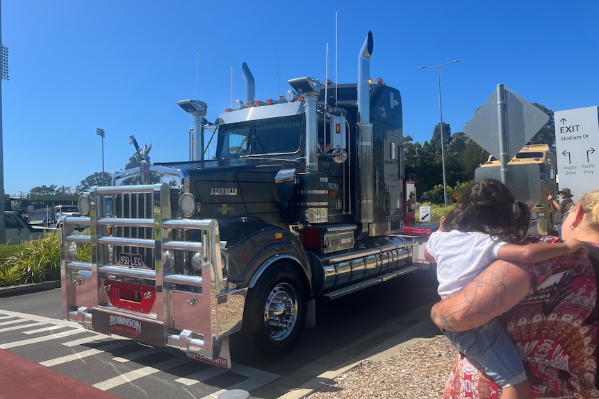 Mum holds baby watching truck drive past