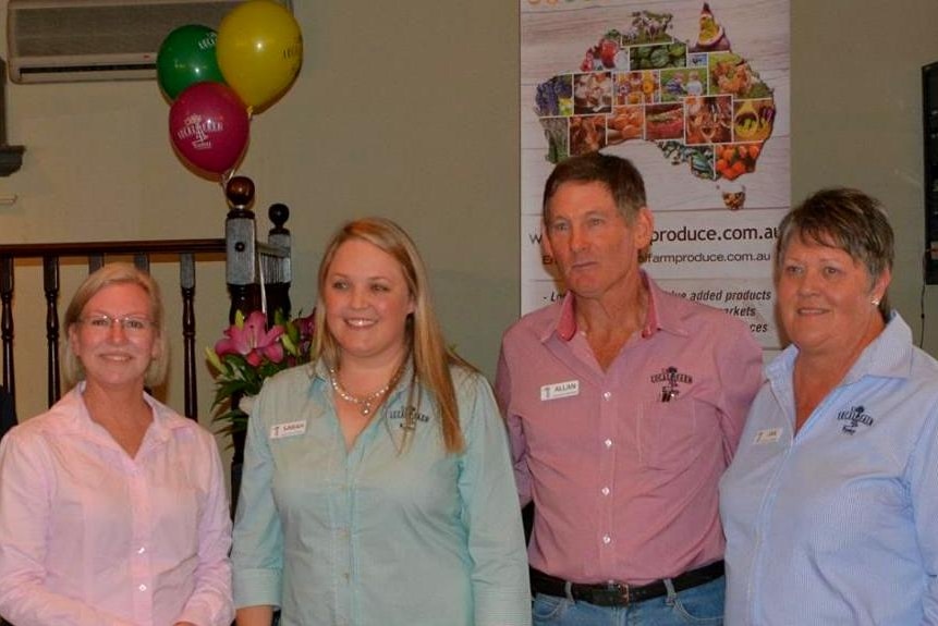 Six people stand in front the Local Farm Produce banner.