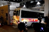 A police van enters through the gates of a Hong Kong police station as reporters record footage.