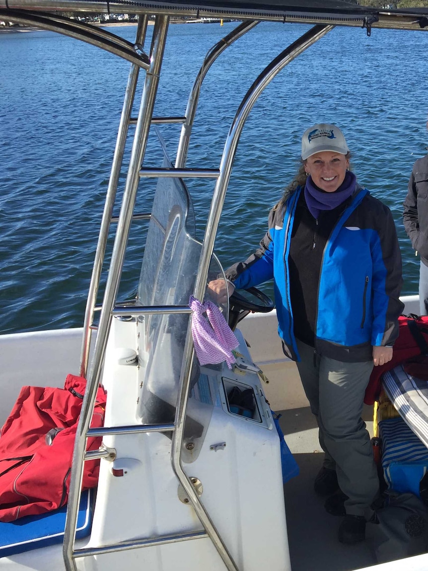 Three people stand under a canopy on a small research boat.