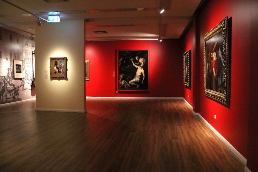 A dimly lit gallery exhibiting baroque artworks