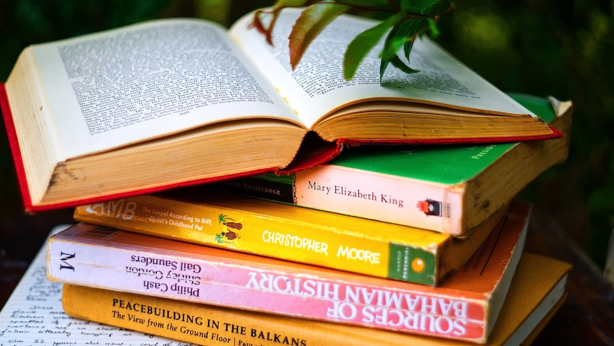 A stack of books, one open, on a table.